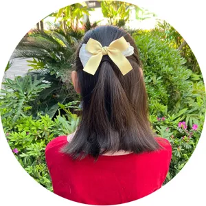 Disparo de detalle de pinza de pelo con lazo de satén amarillo para niños en un jardín al aire libre.