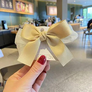 Primer plano de pinza para el pelo con lazo de satén dorado y malla blanca para niñas.