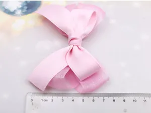 Detalle de pinza de pelo con lazo de malla rosa, accesorio dulce con regla de medida.