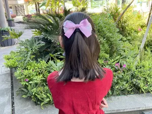 Detalle de pinza para el pelo con lazo de malla rosa, accesorio ideal para niñas en verano.