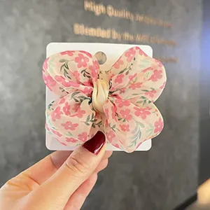 Jolie pince nœud en mousseline florale pour enfants, détail d'accessoire de coiffure printemps été.