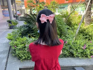 Children's pink fabric ruffled bow hair clip, cute and textured girl hair accessory detail.