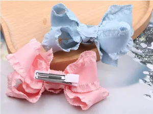 Detailed view of cute children ruffled bow hair clip, fabric side hairpin in pink and blue.