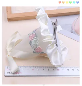 Children white satin hair clip with delicate floral embroidery and sweet ruffled design for girls.