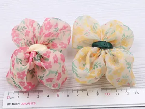 Gros plan de pinces à cheveux nœud en mousseline florale pour enfants avec tissu et couleurs.