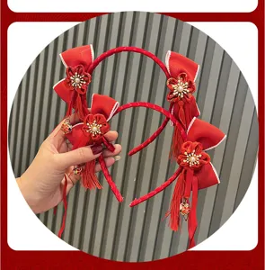 Red festive hair hoop detail featuring cute fabric bows, plum flowers and delicate hanging tassels.