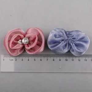 Nahaufnahme handgemachter Cloud-Garn-Blumenaccessoires mit Strassblatt und blauer Schleife.