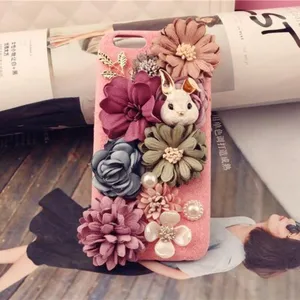 Handgefertigte Handyhülle mit Stoffblumen, Perlen und süßem Kaninchen-Anhänger im Detail.