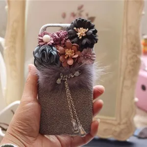 Detailaufnahme der handgemachten Plüschblumen-Handyhülle mit Perlen und Liebe-Anhänger weich.