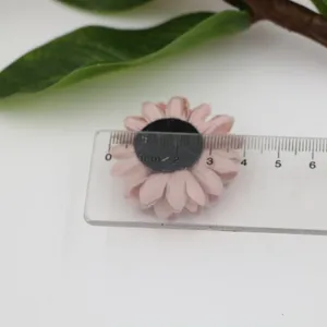 Detaillierte Nahaufnahme von handgemachten rosa Mikrofaser-Blumen-Accessoires mit Lineal.