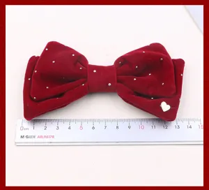 Primo piano di molletta per capelli con fiocco in velluto rosso, strass e cuore in metallo.