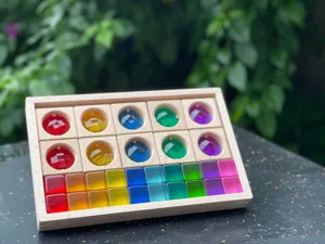 Close-up detail of rainbow acrylic blocks in wooden storage box, ideal for light table and kids.