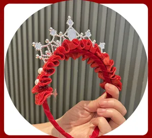 Close-up view of a festive red velvet crown headband with sparkling rhinestones and delicate pearl accents.