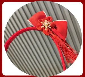 Red festival hairband detail with bow, fabric plum flower, and elegant hanging tassel.