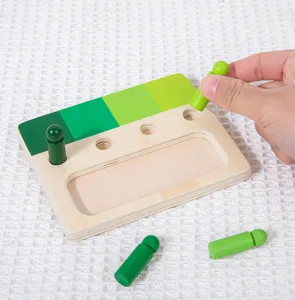 Close-up detail of Montessori wooden color sorting board with gradient green pegs and hand.