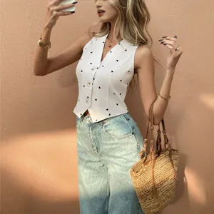 Stylish women's white v-neck vest with cute black heart print paired with denim jeans.