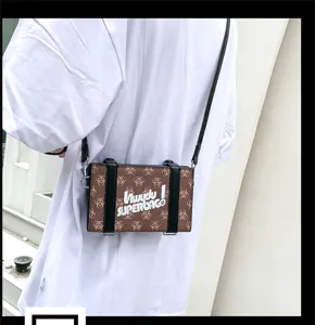 Detailaufnahme der modischen braunen Box-Umhängetasche mit schwarzen Riemen und coolem Print.