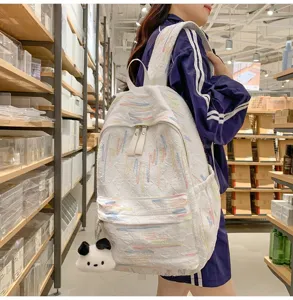 Modischer weißer Rucksack mit bunten bestickten Linien und süßem Plüschanhänger für den Alltag.