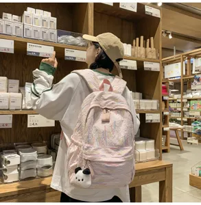 Detailansicht des rosa strukturierten Schulrucksacks mit niedlichem Plüsch-Pandabär Anhänger.
