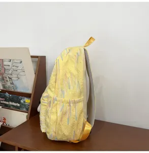 Detailansicht eines gelben Rucksacks von der Seite mit geprägtem Muster und metallenen Trägern.