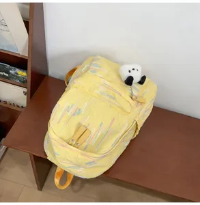 Detailansicht des gelben Rucksacks mit bunter Stickerei und süßem Panda-Plüsch-Anhänger.