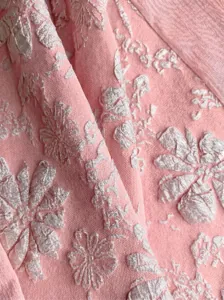 Close-up detail of elegant pink embossed floral fabric texture for fashionable autumn dress style.