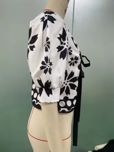 Detail view of black and white floral print short sleeve blouse with puff sleeves and side tie.
