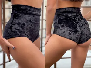 Detail shot showing the high-waisted black velvet texture and slim fit design of the shorts.