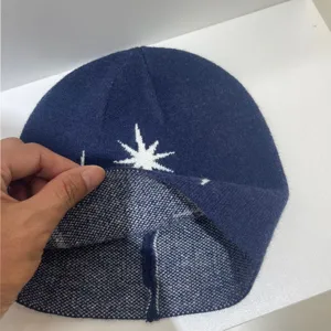 Vista detallada de gorro de punto azul marino con motivo de estrella y textura suave.