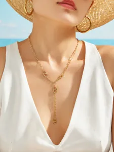 Detailed shot of a delicate gold Y-shaped necklace worn by a model at the sunny beach.