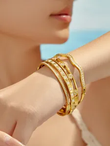 Close-up detail of multi-layer gold metal crystal bracelets worn on wrist, chic design.