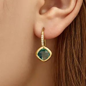 Close-up view of elegant green crystal pendant earring worn on ear, detailed jewelry showcase.