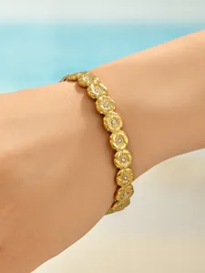 Nahaufnahme des vergoldeten Edelstahl-Blumenarmbands mit funkelnden Steinakzenten am Handgelenk.