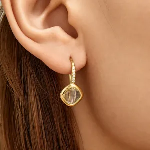 Detailed close-up of gold-tone leverback earrings with pavé cubic zirconia and clear glass.