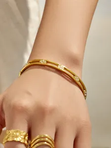 Detail view of the multi-layer gold metal bangle with zircon flowers on wrist.