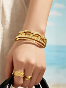 Chic multi-layer zirconia metal bangle stack, exquisite lifestyle hand detail shot.