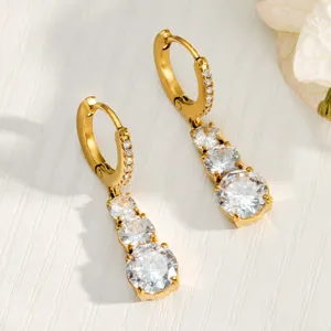 Close-up detail of luxury triple zircon dangle earrings with gold plated huggie hoops.