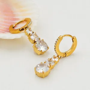 Close-up detail view of golden PVD plated triple zirconia teardrop dangling hoop earrings.
