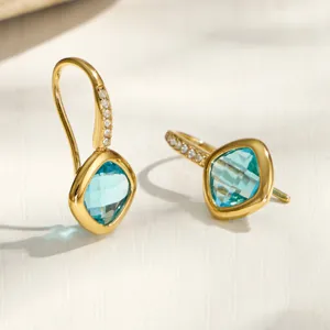 Gold stainless steel drop earrings featuring light blue cushion cut glass and cubic zirconia stones.
