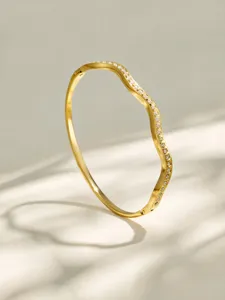 Elegant gold plated wave bangle bracelet with sparkling zirconia stones for women detail view.