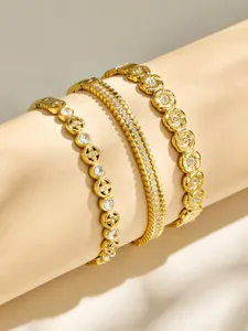 Detailansicht von drei trendigen vergoldeten Edelstahl Armbändern mit funkelnden Zirkonia.