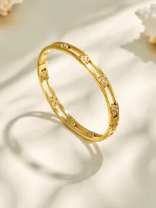 Close-up detail shot of the double-band gold metal clover bracelet with sparkling cubic zirconia.