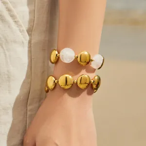 Detail view of minimalist gold-plated stainless steel round disc stackable fashion bracelets.