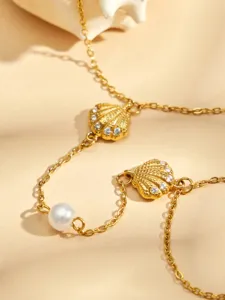 Exquisita cadena de mano de acero de titanio chapado en oro 18K con concha y perla.