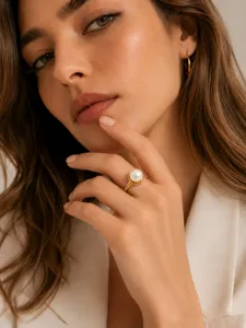 Nahaufnahme Detailansicht eines eleganten 18K vergoldeten Perlenrings am Finger des Modells.