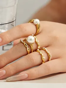 Nahaufnahme von unregelmäßigen, wellenförmigen vergoldeten Ringen mit Perlen für eleganten Stil.