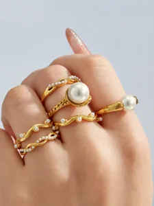 Detailansicht unregelmäßig geschwungener vergoldeter Perlenringe im eleganten Stacking-Design.
