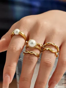 Detailaufnahme unregelmäßig geschwungener vergoldeter Ringe mit eleganten weißen Perlen.