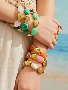 Gros plan détaillé du bracelet élégant multicouche en résine et perles métalliques au poignet.
