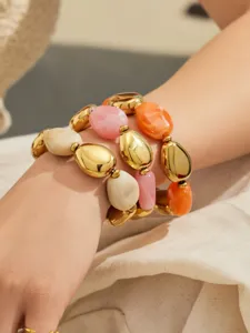 Gros plan détaillé du bracelet multicouche en résine épaisse et perles dorées porté au poignet.